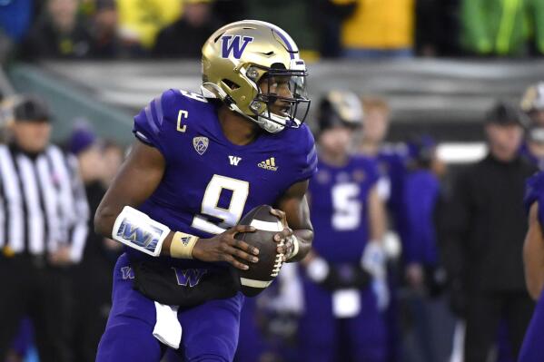 Washington quarterback Michael Penix Jr. (9) rolls away from Oregon defenders and looks for a receiver during the first half of an NCAA college football game Saturday, Nov. 12, 2022, in Eugene, Ore. (AP Photo/Andy Nelson)