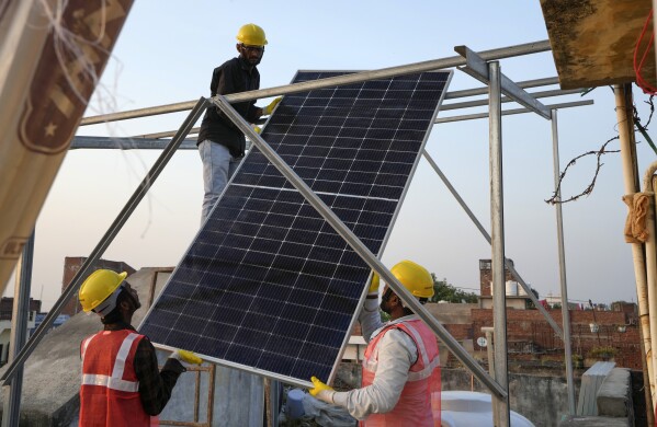 Solar installers work on a rooftop system at a home in Prayagraj, India, Oct. 14, 2024. (AP Photo/Rajesh Kumar Singh, File)