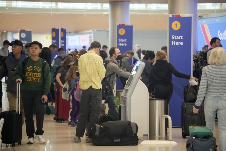 Travelers queue up to check in at self-service ticketing kiosks for Southwest Airlines in Denver International Airport on Monday, Nov. 20, 2023, in Denver. Despite inflation and memories of past holiday travel meltdowns, millions of people are expected to hit airports and highways in record numbers over the Thanksgiving Day break. (AP Photo/David Zalubowski)