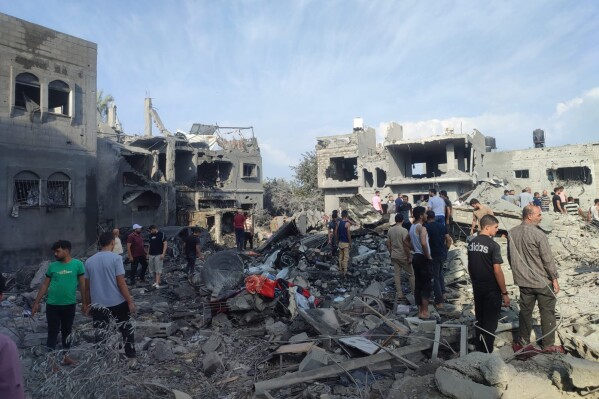 In this photo provided by the al-Agha family, residents of an area in Gaza's western Khan Younis inspect the rubble in the aftermath of an airstrike on the family home of Mohanad al-Agha, who was killed along with his wife, two toddler daughters, father and mother and four of his six brothers in an Israeli airstrike on Oct. 11, 2023. (Courtesy al-Agha family via AP)