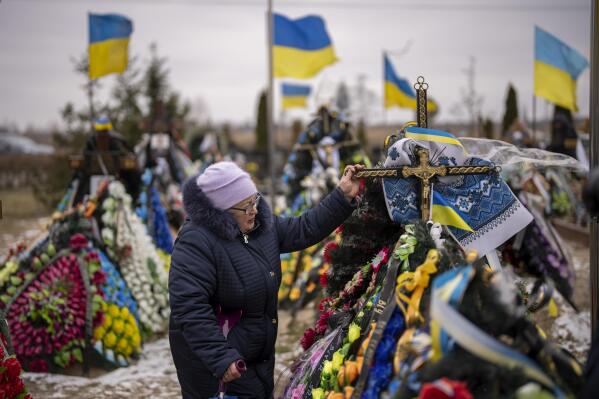 Maria Kurbet, 77, cries at the grave of her son, a military serviceman killed in Bakhmut, during a memorial service to mark the one-year anniversary of the start of the Russia Ukraine war, in a cemetery in Bucha, Ukraine, Friday, Feb. 24, 2023. (AP Photo/Emilio Morenatti)