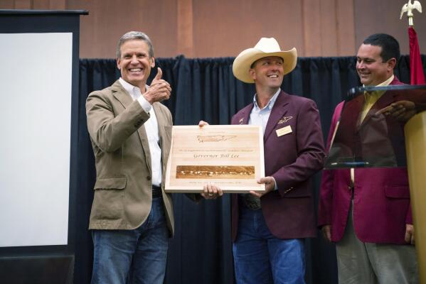 This photo provided by the State of Tennessee shows Tennessee Gov. Bill Lee receiving an award from Dustin Pearson, Tennessee Cattlemen’s Association President-Elect at the Tennessee Cattlemen’s Association annual convention on July 30, 2021 in Sevierville, Tenn. Despite having some of the lowest COVID-19 vaccination rates in the country, Tennessee isn’t planning to offer any incentives for people to get the shot. But it’s a different story when it comes to cattle, where the state has reimbursed farmers nearly half a million dollars over the past two years to vaccinate their herds against respiratory and other diseases. At right is Jay Yeargin, Tennessee Cattlemen’s Association President. (State of Tennessee via AP)