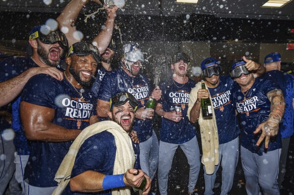 The New York Mets celebrate in the locker room after clinching a playoff berth with a victory in the first baseball game of a doubleheader against the Atlanta Braves, Monday, Sept. 30, 2024, in Atlanta. (AP Photo/Jason Allen)