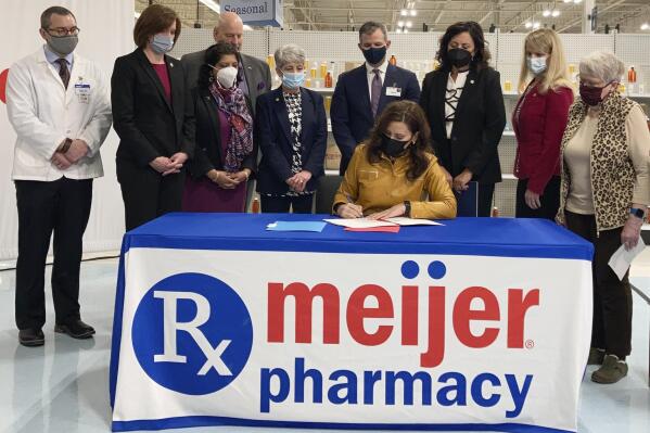 Gov. Gretchen Whitmer signs legislation that is designed to lower prescription drug costs during an event on Wednesday, Feb. 23, 2022, at a Meijer store in Delta Township, Mich. (AP Photo/David Eggert)