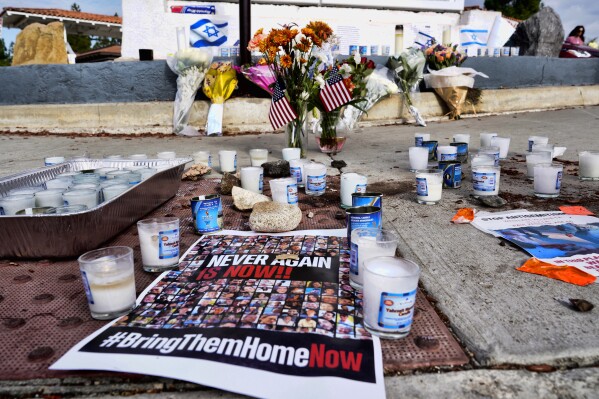 Flowers and candles are left at a makeshift shrine placed at the scene of a Sunday confrontation that lead to death of a demonstrator, Tuesday, Nov. 7, 2023, in Thousand Oaks, Calif. Paul Kessler, 69, died at a hospital on Monday from a head injury after witnesses reported he was involved in a 
