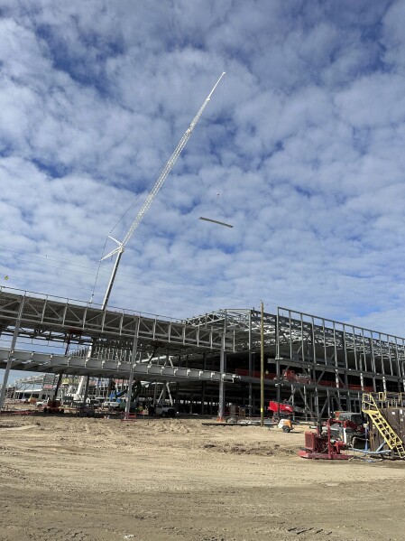 A crane lowers materials onto a building under construction at Hyundai's first U.S. plant for manufacturing electric vehicles on Oct. 25, 2023, in Ellabell, Ga. Hyundai and battery-making partner LG Energy Solution are investing $7.6 million in the sprawling plant site west of Savannah, Ga, where the companies plan to make 300,000 electric vehicles and the batteries that power them each year. (AP Photo/Russ Bynum)