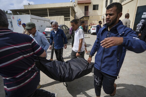 People carry the bodies of Palestinians who were killed in an Israeli airstrike in Nuseirat into the Al Aqsa hospital in Deir al Balah, Gaza Strip, Saturday, April 27, 2024. (AP Photo/Abdel Kareem Hana)