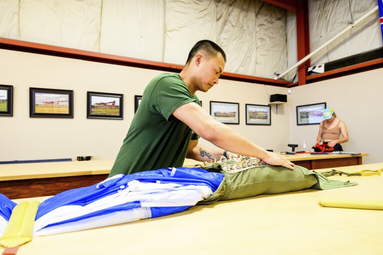 Canadian smokejumper David Pon rigs a parachute on Wednesday, June 5, 2023, in Fort St. John, British Columbia. (AP Photo/Noah Berger)