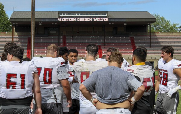 Western Oregon players gather during NCAA college football practice, Wednesday, Aug. 9, 2023, in Monmouth, Ore. As one of just two Division II schools with football teams in on the West Coast, Western Oregon spends hundreds of thousands of dollars in travel expenses to compete in the Lone Star Conference against schools in Texas and New Mexico. (AP Photo/Tim Booth)