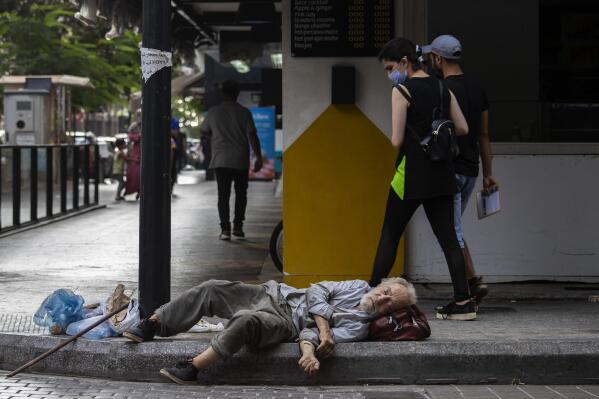 A woman looks to a homeless Lebanese man who sleeps on the ground at Hamra trade street, in Beirut, Lebanon, Friday, July 17, 2020. With virtually no national welfare system, Lebanon’s elderly are left to fend for themselves amid their country’s economic turmoil. In their prime years, they survived 15 years of civil war that started in 1975 and bouts of instability. Now, in their old age, many have been thrown into poverty by one of the world’s worst financial crises in the past 150 years. (AP Photo/Hassan Ammar)