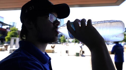 Nathan Darr drinks water while working security outside in Arlington, Texas, Monday, June 26, 2023. (AP Photo/LM Otero)