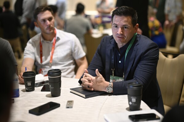 Seattle Seahawks head football coach Mike Macdonald, right, talks with reporters during an NFC coaches availability at the NFL football owners meetings, Tuesday, March 26, 2024, in Orlando, Fla. (AP Photo/Phelan M. Ebenhack)