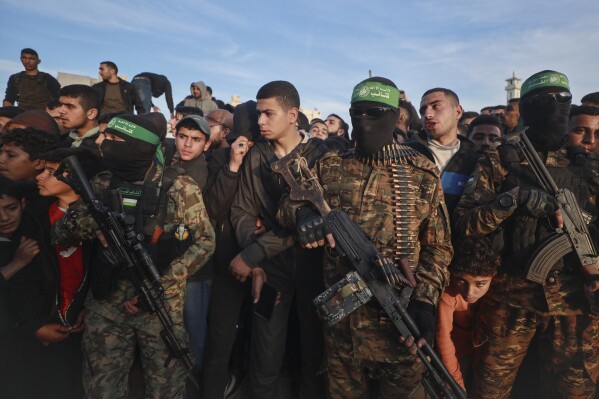 Fighters from the Qassam Brigades, the military wing of Hamas, control the crowd as Red Cross vehicles manoeuvre to collect Israeli hostages to be released under a ceasefire agreement between Israel and Hamas, in Gaza City, Sunday, Jan. 19, 2025. (AP Photo/Abed Hajjar)