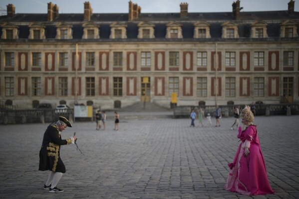 Costumed guests take photos as they arrive at the Great Masked Ball in Versailles, outside Paris, Saturday, June 21, 2025. (AP Photo/Christophe Ena)