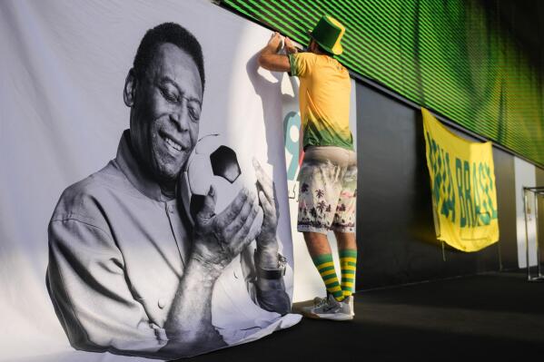 A fan displays a sign in support of Pelé at a Brazilian fan party before the the World Cup round of 16 soccer match between Brazil and South Korea, in Doha, Dec. 5, 2022. The 82-year-old Pelé remained in a hospital in San Paulo recovering from a respiratory infection that was aggravated by COVID-19, but the news coming from Brazil early Monday was good. (AP Photo/Ashley Landis)