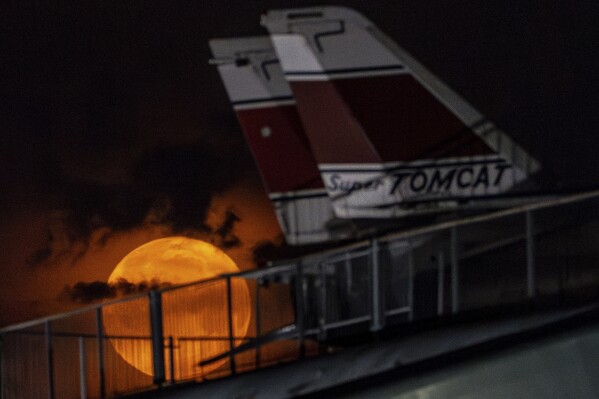 The flower moon sets behind Grumman F-14 Tomcat fighter jets at the Intrepid Museum, Thursday, May 23, 2024, in New York. (AP Photo/Julia Nikhinson)