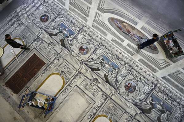 Set designers work on a stage canvas in the "Teatro dell' Opera" opera house warehouse, in Rome, Thursday, April 10, 2025. (AP Photo/Andrew Medichini)