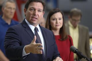 FILE - Florida Governor Ron DeSantis flanked by Attorney General Ashley Moody and supporters addresses the media and supporters Thursday, Oct. 28, 2021 in Lakeland Fla. President Joe Biden’s plan to require vaccinations at all private employers of 100 workers or more has already hit a wall of opposition from Republican governors, state lawmakers and attorneys general.(Calvin Knight/The Ledger via AP)