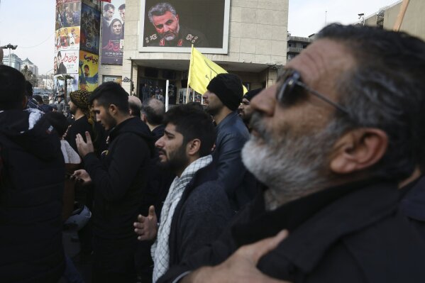 Protesters mourn in a demonstration over the U.S. airstrike in Iraq that killed Iranian Revolutionary Guard Gen. Qassem Soleimani, shown in the screen at rear, in Tehran, Iran, Jan. 3, 2020. Iran has vowed "harsh retaliation" for the U.S. airstrike near Baghdad's airport that killed Tehran's top general and the architect of its interventions across the Middle East, as tensions soared in the wake of the targeted killing. (AP Photo/Vahid Salemi)