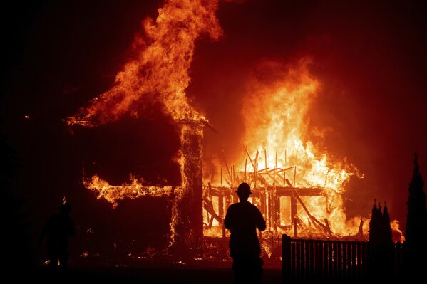 FILE - In this Nov. 8, 2018, file photo, a home burns during a wildfire in Paradise, Calif. Ceremonies will be held in Paradise, Friday, Nov. 8, 2019, to mark the one-year anniversary of the fire, including 85 seconds of silence to remember the 85 people killed. (AP Photo/Noah Berger, File)