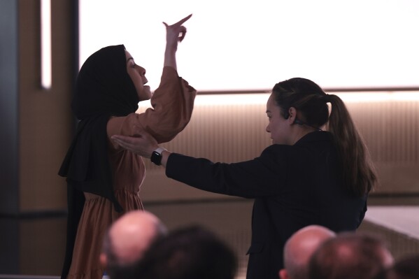 CORRECTS DATE - A pro-Palestinian demonstrator, Ibtihal Aboussad, is escorted away by security as they interrupt Microsoft AI CEO Mustafa Suleyman during a presentation of the company's AI assistant, Copilot, ahead of a 50th Anniversary presentation at Microsoft headquarters, Friday, April 4, 2025, in Redmond, Wash. (AP Photo/Jason Redmond)