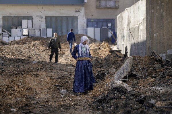 Palestinos caminan por una carretera dañada tras una redada militar israelí en el campo de refugiados de Jenin, Cisjordania, el viernes 17 de noviembre de 2023. Las fuerzas israelíes mataron a tres palestinos durante la noche en la redada, dijo el viernes el Ministerio de Salud palestino.  El grupo militante Hamás dijo que los dos eran sus miembros.  (Foto AP/Majdi Mohammed)