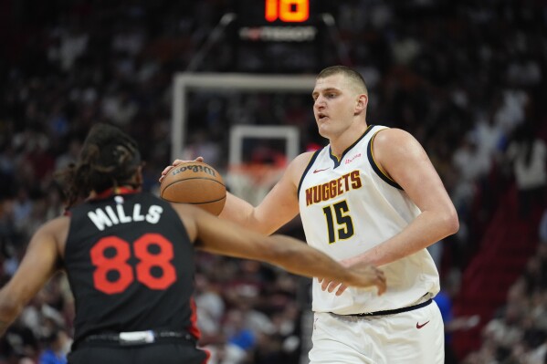 Denver Nuggets center Nikola Jokic (15) carries the ball downcourt defended by Miami Heat guard Patty Mills (88) during the first half of an NBA basketball game, Wednesday, March 13, 2024, in Miami. (AP Photo/Rebecca Blackwell)