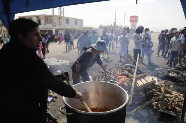 People prepare a communal stew for protesters blocking the Pan American highway during a truckers strike in Ica, Peru, Tuesday, April 5, 2022. Peru's President Pedro Castillo imposed a curfew on the capital and the country's main port in response to sometimes violent protests over rising prices of fuel and food, requiring people in Lima and Callao to mostly stay in their homes all of Tuesday. (AP Photo/Guadalupe Pardo)