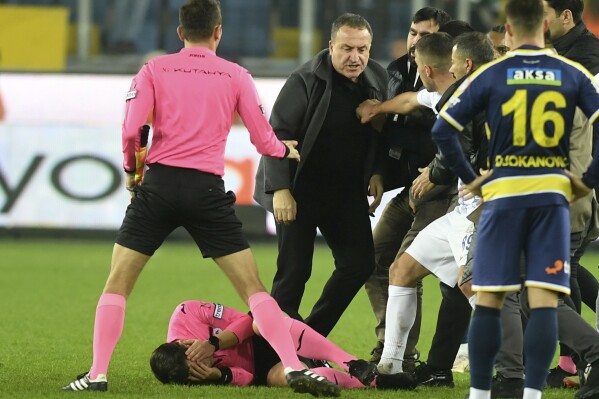 FILE - Referee Halil Umut Meler holds his face as he lies on the ground after being punched by MKE Ankaragucu president Faruk Koca, center, at the end of the Turkish Super Lig soccer match between MKE Ankaragucu and Caykur Rizespor in Ankara, Dec. 11, 2023. Koca, the former president of a Turkish top division soccer team told a court on Tuesday Jan. 9, 2024, that he regretted attacking a referee at the end of a league game but denied having threatened him with death. (Abdurrahman Antakyali/Depo Photos via AP, File)