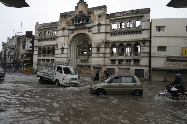 Motorcyclists and cars drive through a flooded road caused by heavy monsoon rainfall in Lahore, Pakistan, Thursday, Aug. 1, 2024. (AP Photo/K.M. Chaudary)