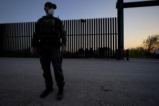 FILE - In this March 21, 2021 file photo, a U.S. Customs and Border Protection agent looks on near a gate on the U.S.-Mexico border wall as agents take migrants into custody, in Abram-Perezville, Texas. Texas Gov. Greg Abbott has has offered scarce details on his plans to construct new barrier along the border with Mexico. It remained unclear Friday, June 11 on how much barrier Texas would erect or where or when it would be installed on the state's 1,200-mile border with Mexico.  (AP Photo/Julio Cortez, File)