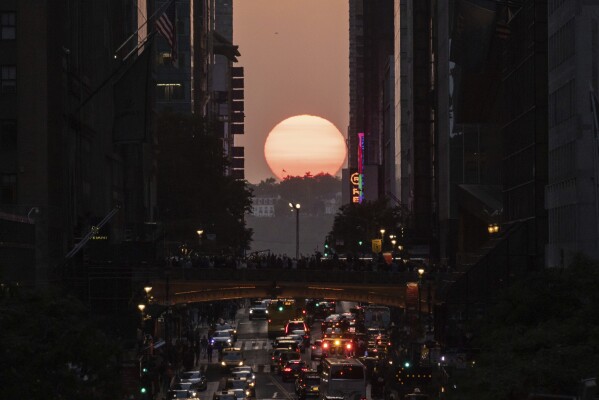FILE - The sun sets between buildings along 42nd Street in New York during a phenomenon known as "Manhattanhenge," May 30, 2023. Twice per year, New Yorkers and visitors are treated to a phenomenon known as Manhattanhenge, when the setting sun aligns with the Manhattan street grid and sinks below the horizon framed in a canyon of skyscrapers. Manhattanhenge happens for the first time this year on Tuesday, May 28, at 8:13 p.m. and Wednesday, May 29, at 8:12 p.m. (AP Photo/Yuki Iwamura, File)