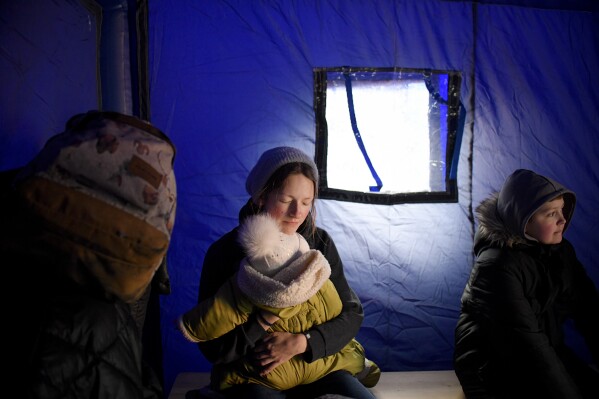FILE.- A refugee fleeing the conflict from neighbouring Ukraine holds her baby as she sits in a tent at the Romanian-Ukrainian border, in Siret, Romania, Saturday, Feb. 26, 2022. As a woman photojournalist Andreea thinks "it is tougher as a woman in professions regarded as male territory but it's not at all hopeless: just a few generations ago, most professions were considered "men only," and that changed so drastically that it's hard to imagine times like that ever existed."(AP Photo/Andreea Alexandru,File)