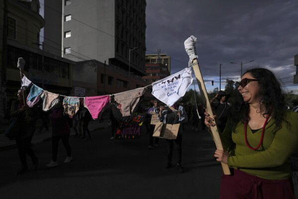 A woman holds a makeshift clothesline of underwear marked with various female empowerment messages including, "Don't give your opinion if it's not your body", during a march marking International Women's Day in Quito, Ecuador, Friday, March 8, 2024. (AP Photo/Dolores Ochoa)