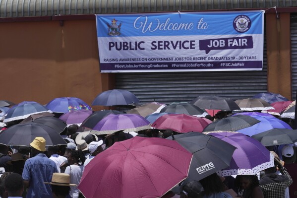 Young people wait outside the entrance to a government job fair, in Harare, Wednesday, Dec. 6, 2023. Hundreds attended the fair for a chance to be registered in a database of job seekers. A stampede at the fair left some people with injuries. (AP Photo/ Tsvangirayi Mukwazhi)