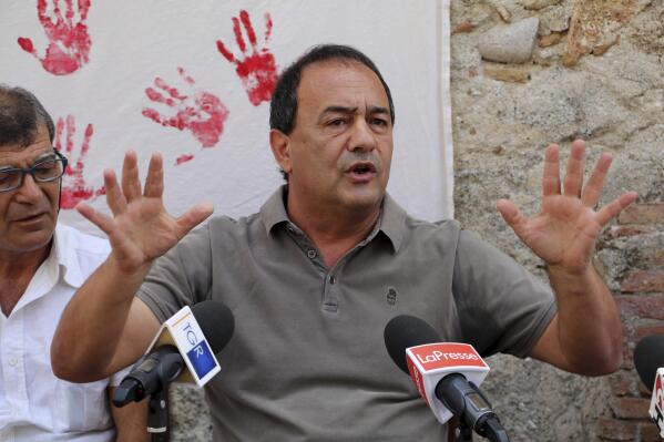In this photo taken on Sept. 2019, the former mayor of Riace, in Southern Italy, Domenico "Mimmo" Lucano receives media attention.  A court in southern Italy on Thursday, Sept. 30, 2021, convicted Lucano, who was mayor of a tiny town dubbed “the town of welcome” of aiding illegal immigration and sentenced him to 13 years and two months in prison. Prosecutors alleged that Lucano facilitated marriages of convenience between Italian men in the town of Riace and foreign women to get the women Italian residency permits. (Luigi Salsini/LaPresse via AP)