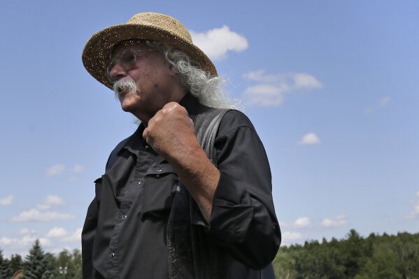 Woodstock veteran Arlo Guthrie reacts after playing a song at the original site of the 1969 Woodstock Music and Arts Fair in Bethel, N.Y., Thursday, Aug. 15, 2019. Guthrie is schedule to play a set on the top of hill nearby but told reporters he wanted to play at least one song on the original 1969 site. Woodstock fans are expected to get back to the garden to mark the 50th anniversary of the generation-defining festival. Bethel Woods Center for the Arts is hosting a series of events Thursday through Sunday at the bucolic 1969 concert site, 80 miles (130 kilometers) northwest of New York City. (AP Photo/Seth Wenig)