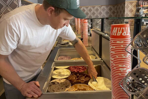 Salt & Straw Ice Cream Co-Founder Tyler Malek scoops "Day-Old Bread Pudding" upcycled ice cream in Los Gatos, Calif., on June 2, 2023. (AP Photo/Haven Daley, File)
