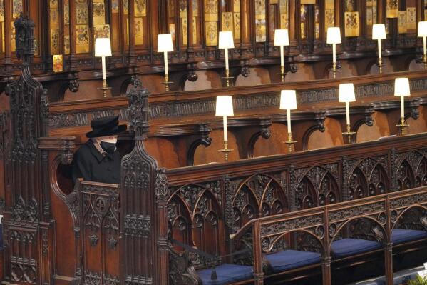 FILE - Britain's Queen Elizabeth II sits alone in St. George's Chapel during the funeral of Prince Philip, the man who had been by her side for 73 years, at Windsor Castle, Windsor, England, Saturday April 17, 2021. Boris Johnson's former communications chief has apologized "unreservedly" on Friday for a lockdown-breaching party in Downing Street last year. The Daily Telegraph said Downing Street staff drank, danced and socialized on April 16 last year, the night before the funeral of Prince Philip. The next day, the widowed Queen Elizabeth II sat alone in the church during her husband's funeral service in order to adhere to social distancing rules. (Jonathan Brady/Pool via AP, File)