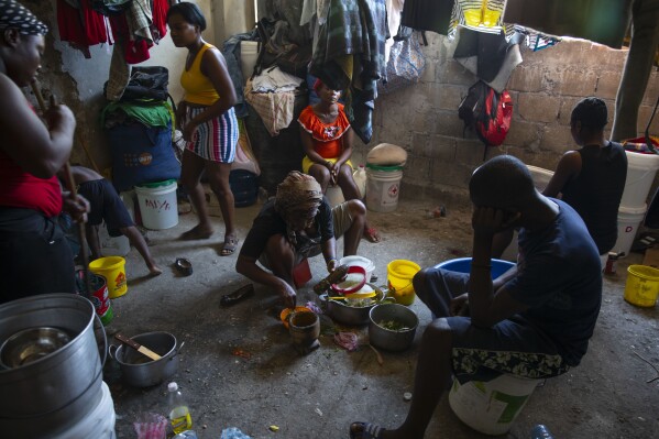 FILE - A woman prepares food at a shelter for families displaced by gang violence in Port-au-Prince, Haiti, Dec. 9, 2021. Catastrophic hunger is so dire in two world hotspots that famine is imminent in northern Gaza and approaching in Haiti, with hundreds of thousands of people in both places struggling to avoid starvation, according to international food security experts and aid groups. (AP Photo/Odelyn Joseph, File)