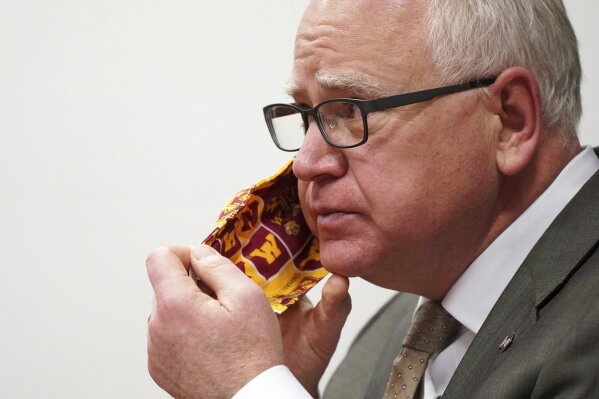 FILE - In this Jan. 26, 2021 file photo, Minnesota Gov. Tim Walz takes off his University of Minnesota cloth face mask to answer a question from a reporter during a press conference in St. Paul, Minn. Gov. Walz is quarantining for 10 days after being exposed to a staff member who tested positive for COVID-19, the governor's spokesman said Wednesday, March 17, 2021. (Anthony Souffle/Star Tribune via AP File)