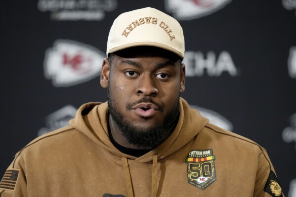 FILE - Kansas City Chiefs guard Trey Smith talks to the media after the NFL football team's practice Friday, Jan. 26, 2024, in Kansas City, Mo. Kansas City Chiefs offensive lineman Trey Smith shared the WWE title belt to help calm a young boy in the aftermath of the mass shooting at the team's Super Bowl celebration, Wednesday, Feb. 14. Smith, who sported the belt during the celebration, noticed the frightened boy, who was with his father.(AP Photo/Charlie Riedel, File)