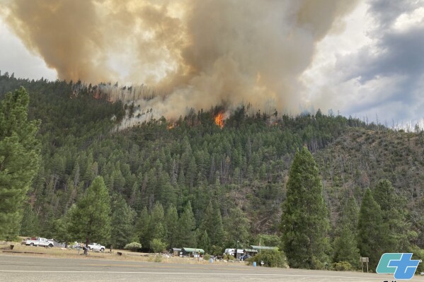 In this photo provided by Caltrans, smoke rises from the Head Fire in Klamath National Forest, Calif., on Tuesday Aug. 15, 2023. A wildfire pushed by gusty winds from a thunderstorm raced through national forest land near California's border with Oregon, prompting evacuations in the rural area. The blaze in Siskiyou County was one of at least 19 fires that erupted in the Klamath National Forest as thunderstorms rolling through the area brought lightning and downdrafts that drove the flames through timber and rural lands. (Roger Matthews/Catrans via AP)