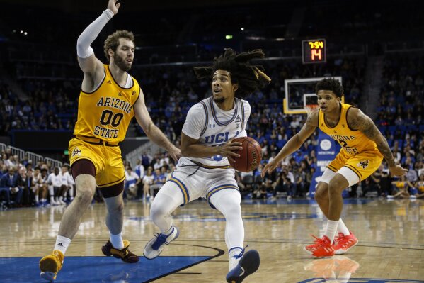 FILE - In this Thursday, Feb. 27, 2020, file photo, UCLA guard Tyger Campbell (10) drives between Arizona State forward Mickey Mitchell (00) and guard Rob Edwards (2) during an NCAA college basketball game, in Los Angeles. Campbell was the only player to start all 31 games during the 2019-20 season, averaging 8.3 points and five assists, most among the Pac-12's returners. (AP Photo/Ringo H.W. Chiu, File)