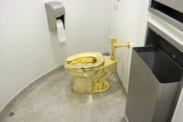 FILE - This Sept. 16, 2016 file image made from a video shows the 18-karat toilet, titled "America," by Maurizio Cattelan in the restroom of the Solomon R. Guggenheim Museum in New York. Four men have been charged over the theft of an 18-carat gold toilet from Blenheim Palace, the sprawling English mansion where British wartime leader Winston Churchill was born. The toilet, valued at 4.8 million pounds, or $5.95 million, was the work of Italian conceptual artist Maurizio Cattelan. (AP Photo, File)