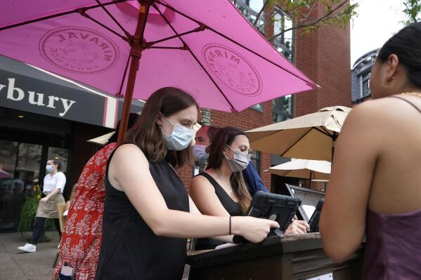 Workers wear masks out of concern for the coronavirus while greeting people at a restaurant on Boston's fashionable Newbury Street, Sunday, Aug. 8, 2021. (AP Photo/Steven Senne)