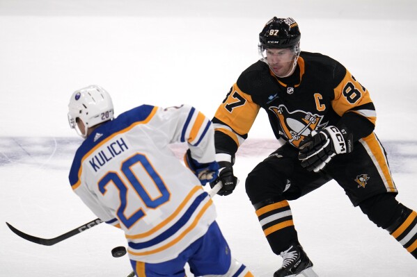 Pittsburgh Penguins' Sidney Crosby (87) knocks the puck off the stick of Buffalo Sabres' Juri Kulich during the first period of a NHL hockey preseason game in Pittsburgh, Thursday, Sept. 28, 2023. (AP Photo/Gene J. Puskar)