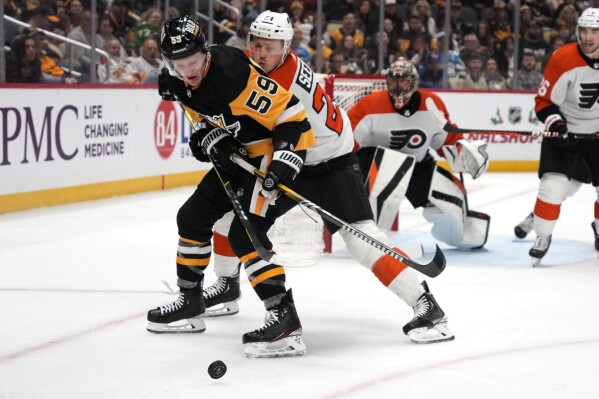 Pittsburgh Penguins' Jake Guentzel (59) works to gain control of the puck with Philadelphia Flyers' Nick Seeler (24) defending during the second period of an NHL hockey game in Pittsburgh, Saturday, Dec. 2, 2023. (AP Photo/Gene J. Puskar)