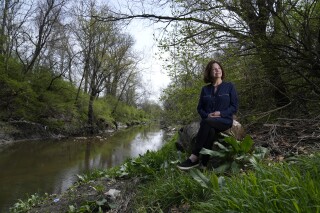 Susie Gaffney poses for a photo along Coldwater Creek near where she used to live Friday, April 7, 2023, in Florissant, Mo. The creek was contaminated when nuclear waste from the Manhattan Project flowed into the waterway past homes, schools and businesses. St. Louis played an important role in the country’s effort to build the first nuclear weapon. (AP Photo/Jeff Roberson)