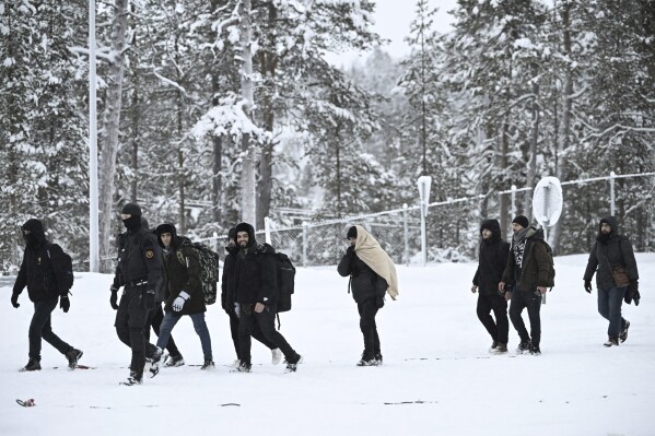 Finnish border guards escort migrants arriving at the Radja Joseppi border crossing between Russia and Finland in Inari, northern Finland, Saturday, November 25, 2023. The European Union's border protection agency said it would deploy dozens of police officers and equipment. Russia has sent reinforcements to Finland to help with border security amid suspicions that Russia is behind the influx of migrants into Finland.  (Emi Korhonen/Retikva, via AP)